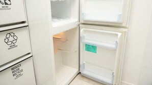 Un réfrigérateur blanc doté d’un compartiment congélateur fermé, d’un récipient à eau et à lait visible, et d’un symbole de recyclage sur le côté.