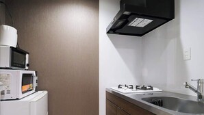Een kleine keuken met een magnetron, koelkast, spoelbak en kookplaat.
