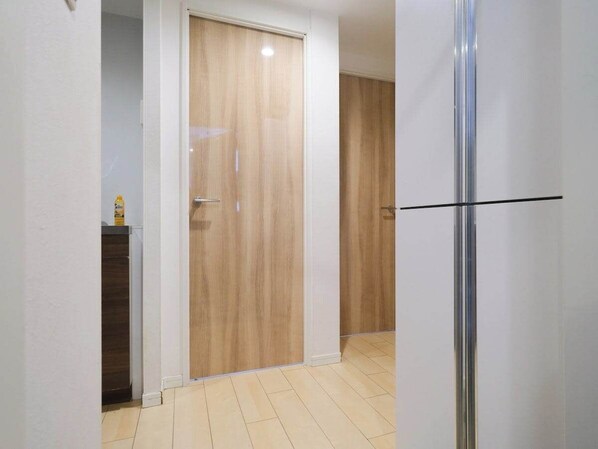 A hallway with a wooden door, a metal door frame, and a tiled floor.