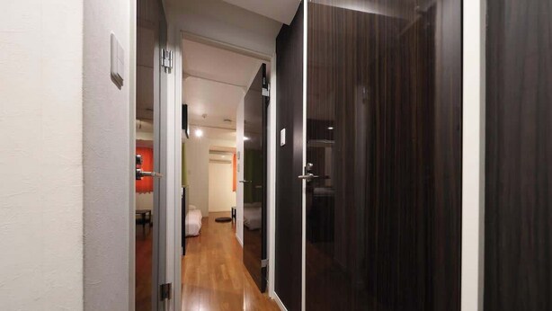 Un pasillo con suelo de madera, una puerta de madera oscura y una pared blanca.