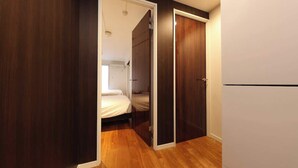 Quarto com uma cama, um guarda-roupa e uma porta que dá para outro cômodo.