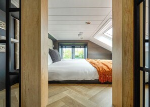 A bedroom with a bed, a window, and a view of greenery. - Glamping Pods with hot tubs (Great Yarmouth)