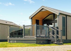A modern building with a covered porch, a staircase, and a large window. - Glamping Pods with hot tubs (Great Yarmouth)