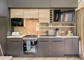 A modern kitchen with built-in appliances, a microwave, a toaster, and a sink. - Glamping Pods with hot tubs (Great Yarmouth)