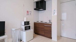 A compact kitchen with a microwave, oven, and stove, a white cabinet, and a black range hood. - 5 minutes walk from Asakusa Sta. (Sumida City)