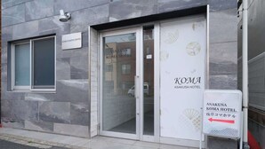 A hotel entrance with a sign for Asakusa Koma Hotel, a glass door, and a directional sign. - 6 minutes walk from Asakusa Sta. (Sumida City)