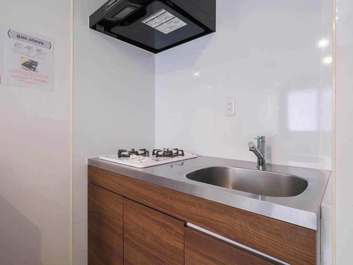 A kitchen with a gas stove, stainless steel sink, and wooden cabinets.