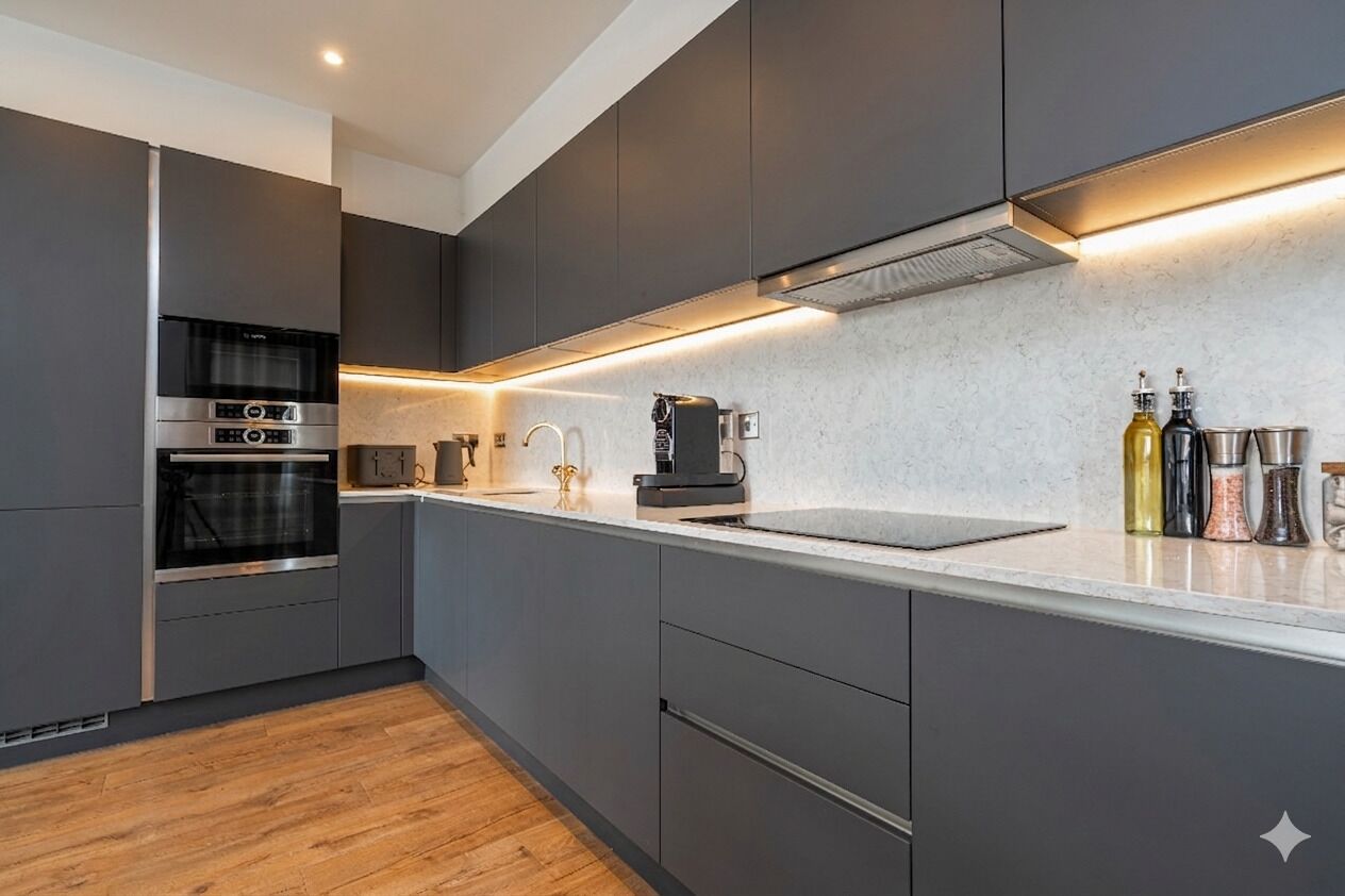 Una cucina moderna con mobili grigi, elettrodomestici in acciaio inossidabile e un piano di lavoro in marmo.