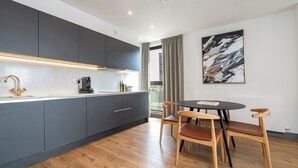 Una cucina moderna con mobili grigi, un tavolo da pranzo in legno con sedie e un grande quadro astratto appeso al muro.