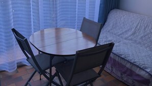 A room with a round table and four chairs, a sofa, and a window with sheer curtains. - T2 with pool, private parking, walking distance to the beach - 4 pers - ARGELES SUR MER (Argelès-sur-Mer)