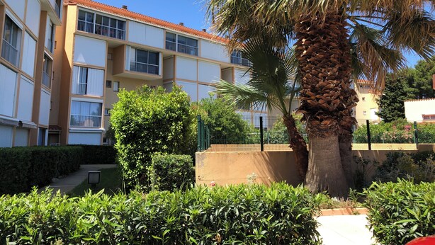 A multi-story building with balconies, a palm tree, and well-maintained greenery. - T2 with pool, private parking, walking distance to the beach - 4 pers - ARGELES SUR MER (Argelès-sur-Mer)
