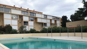 A swimming pool with a tiled deck, surrounded by a low wall and dense shrubbery. - T2 with pool, private parking, walking distance to the beach - 4 pers - ARGELES SUR MER (Argelès-sur-Mer)