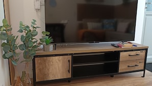 Un mueble de madera para entretenimiento con un televisor de pantalla plana, dos cajones y una planta pequeña.