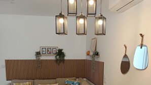 Un espacio moderno para vivir con una mesa de comedor de madera, sillas blancas, un sofá con cojines estampados e iluminación colgante.