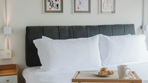 A neatly made bed with a tray of breakfast items, a bedside table with a lamp, and three abstract art pieces on the wall. - Modern 1BR in Juárez with fast WiFi, great natural light, a comfortable king bed, a fully equipped kitchen, and a luxury bathroom. Perfect for couples or solo travelers seeking comfort, style, and a prime location in Mexico City. (Cuauhtémoc)