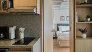 A modern kitchen with a microwave, stove, and utensils, leading to a bedroom with a bed and bedside table. - Modern 1BR in Juárez with fast WiFi, great natural light, a comfortable king bed, a fully equipped kitchen, and a luxury bathroom. Perfect for couples or solo travelers seeking comfort, style, and a prime location in Mexico City. (Cuauhtémoc)