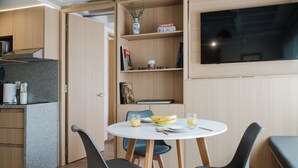Eine moderne Küche mit Essbereich, einem Flachbildfernseher und einem Bücherregal.