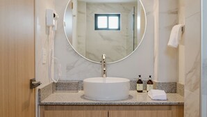 Ein Badezimmer mit rundem Spiegel, Waschbecken und Handtuchhalter.