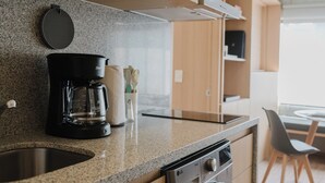 Eine moderne Küche mit Holzschränken, einer integrierten Waschmaschine, einer Kaffeemaschine und einer Mikrowelle.