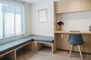 A room with a bench, a desk, a chair, a vase with flowers, and a framed picture on the wall. - Modern 1BR in Juárez with fast WiFi, great natural light, a comfortable king bed, a fully equipped kitchen, and a luxury bathroom. Perfect for couples or solo travelers seeking comfort, style, and a prime location in Mexico City. (Cuauhtémoc)