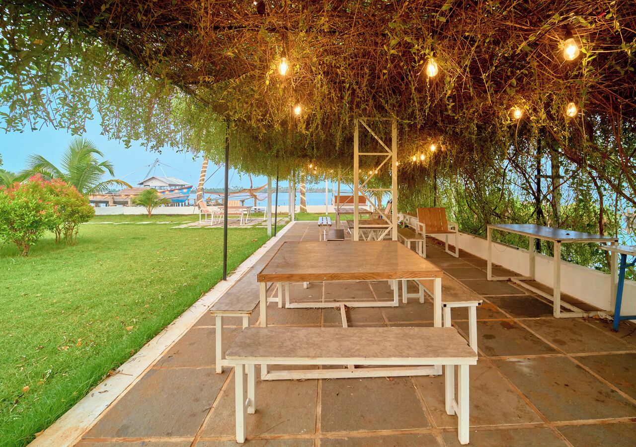 Een terras buiten met picknicktafels en lichtjes.