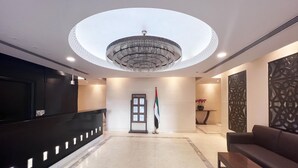 A modern lobby with a reception desk, a chandelier, a flag, and a sofa. - GMA Amwaj 2BR Sea View High Floor (Dubai)