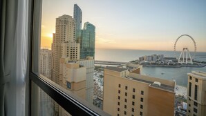 A cityscape with high-rise buildings, a Ferris wheel, and a body of water. - GMA Amwaj 2BR Sea View High Floor (Dubai)