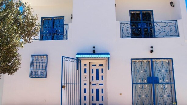 Un edificio blanco con marcos de ventana azules y una puerta central.