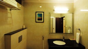 Un baño con lavamanos, espejo, toallero y un cuadro en la pared.