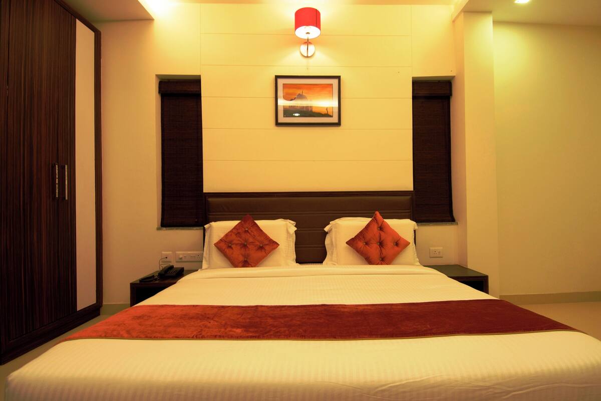 A hotel room with a large bed, a nightstand, a telephone, and a wall-mounted picture.