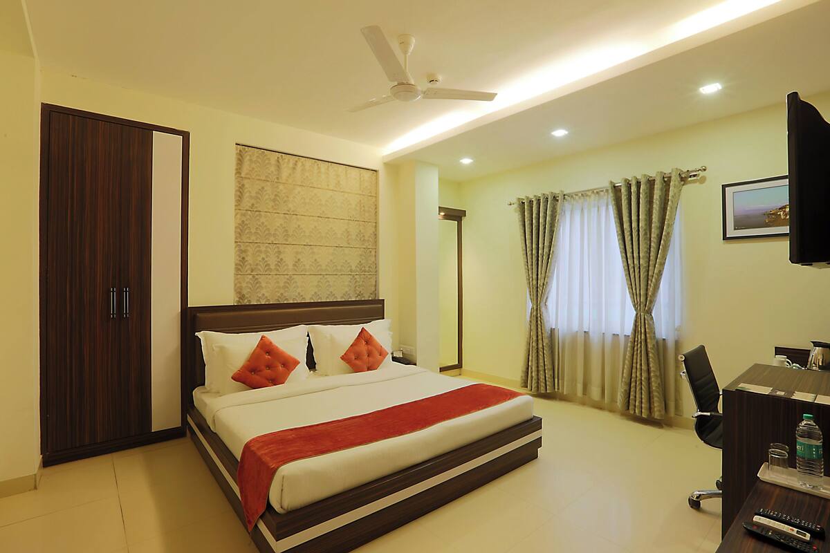 A hotel room with a bed, a desk, a chair, a television, and a ceiling fan.