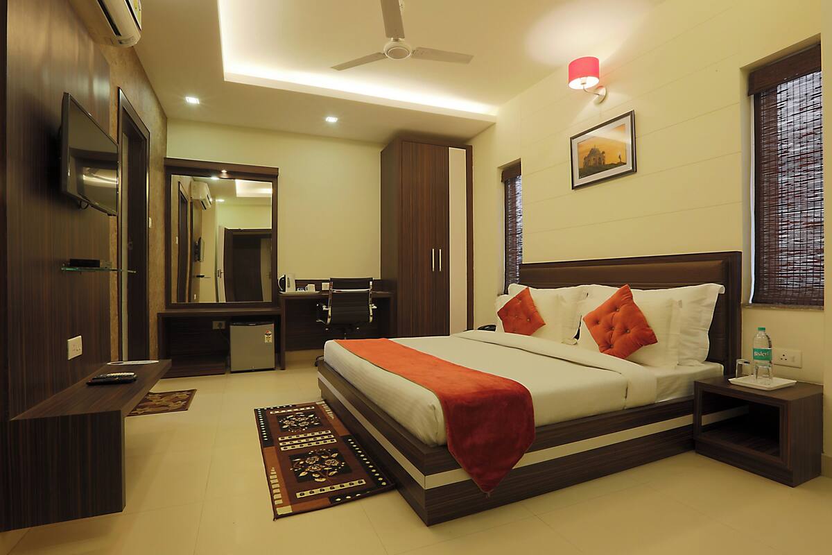 A hotel room with a bed, desk, wardrobe, and a ceiling fan.
