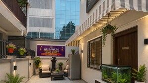 Un patio de hotel con un letrero de recepción, plantas en macetas, un área de descanso y un acuario.