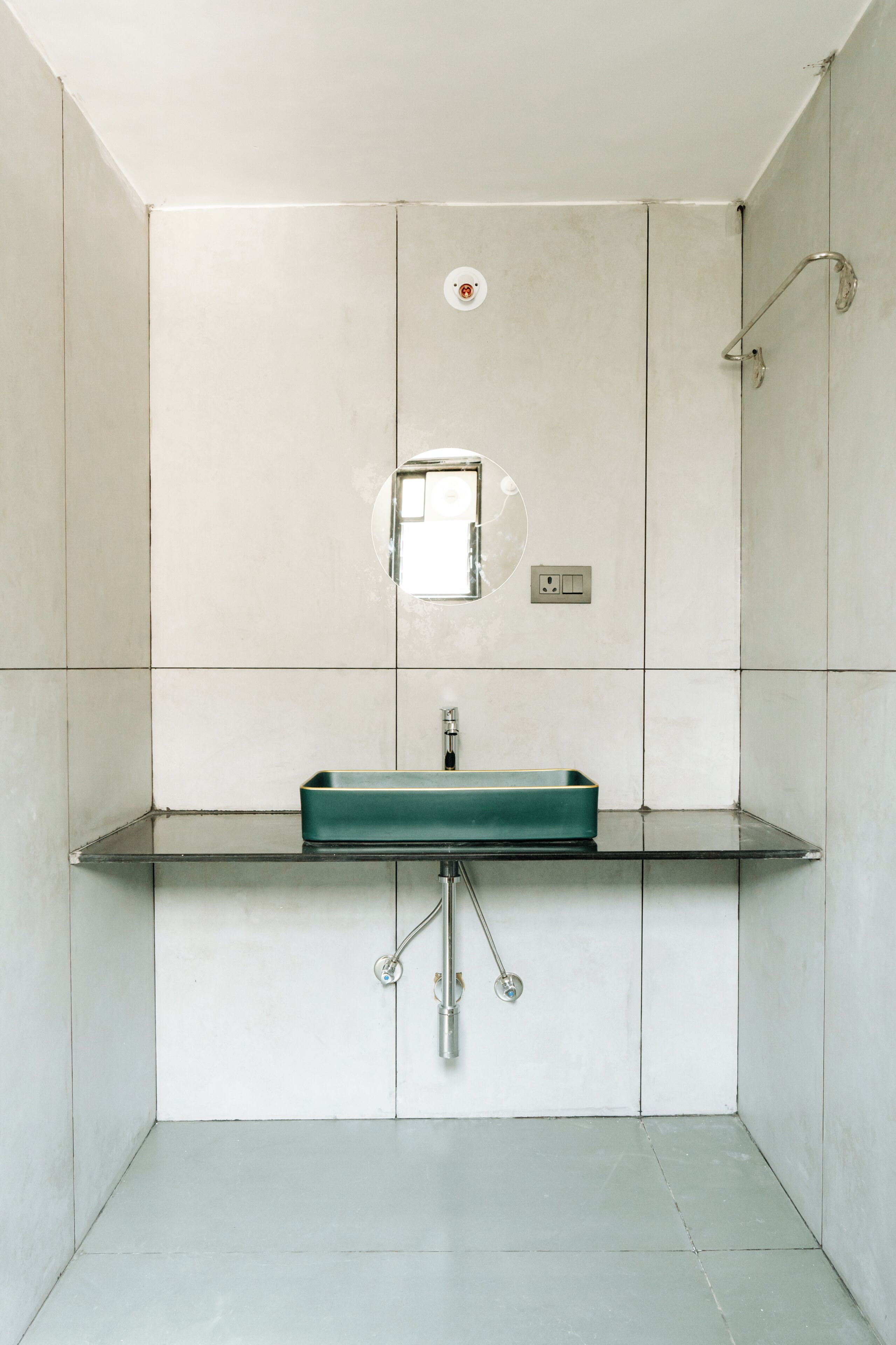 Ein Badezimmer mit einem rechteckigen Waschbecken, einem Spiegel und einer Dusche.