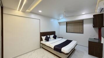 Un dormitorio moderno con cama, ventilador de techo, ventana con persianas y armario empotrado.