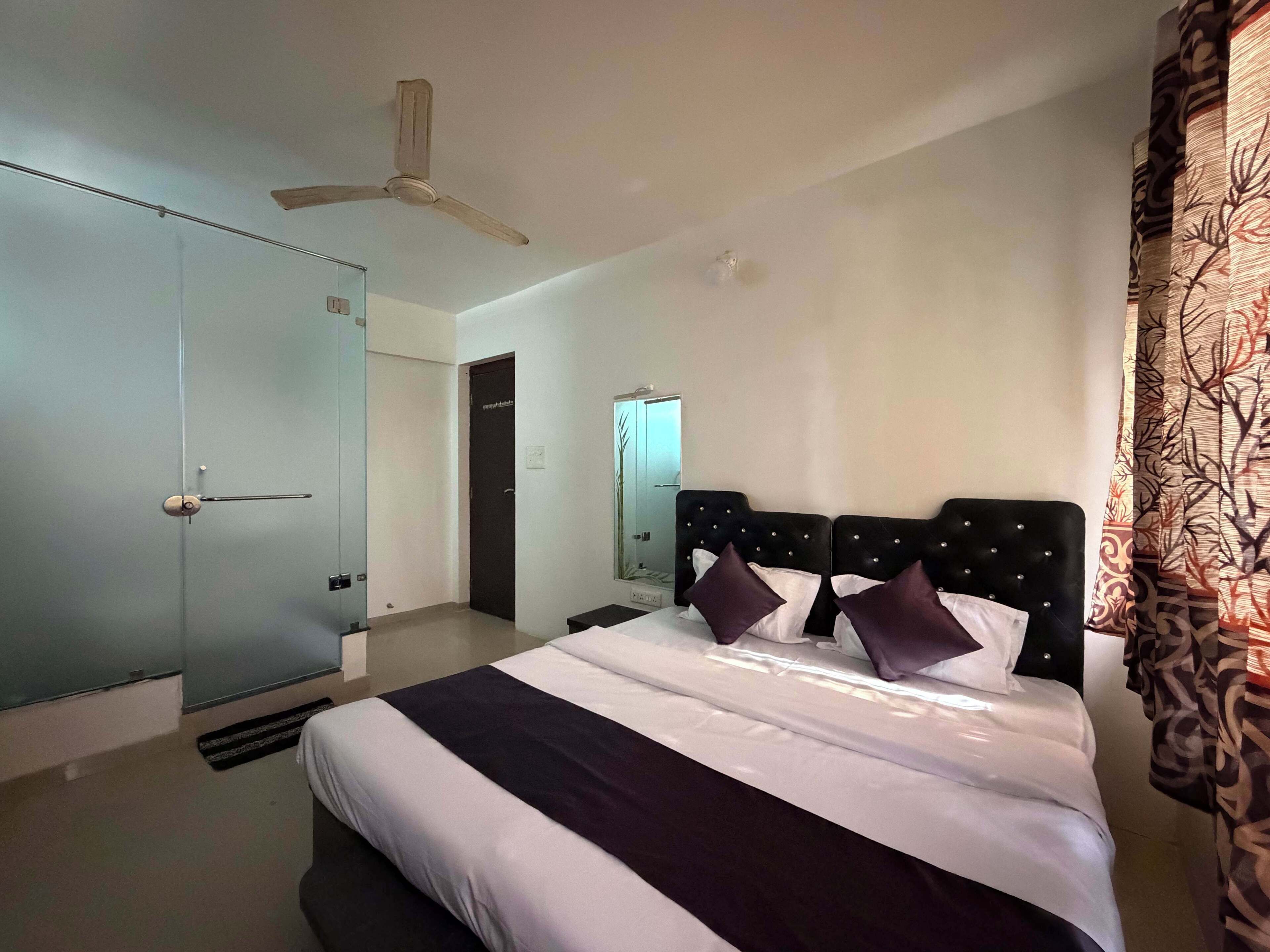 Una habitación de hotel con cama, ventilador de techo, armario y espejo.