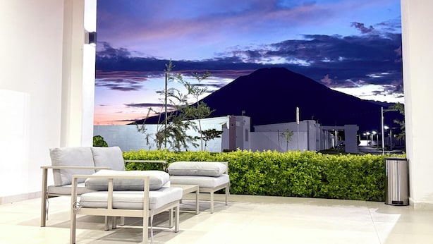A modern interior with a mural of a mountain at sunset, a seating area with white furniture, and a green hedge. - Enjoy your getaway at this unique, private, quiet and safe residential house! (San Miguel)