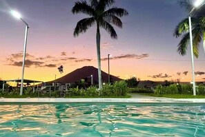 Une piscine bordée de palmiers, avec une montagne en arrière-plan.