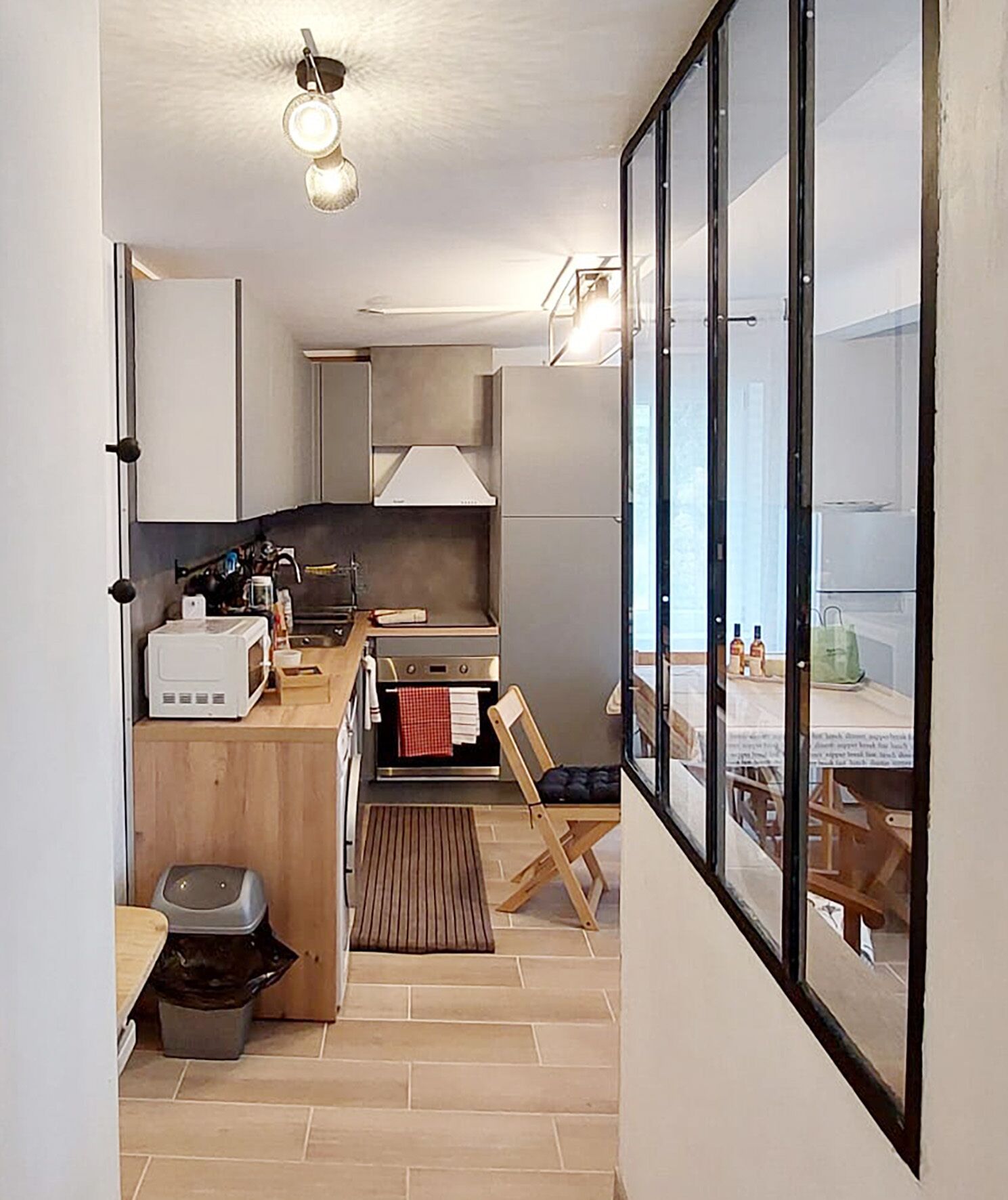 Une cuisine compacte équipée d’un four à micro-ondes, d’un four traditionnel et d’un petit coin repas avec une chaise et une table.