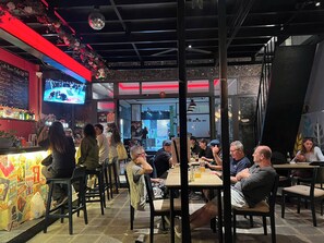 Een restaurant met een bar, tafels en stoelen.
