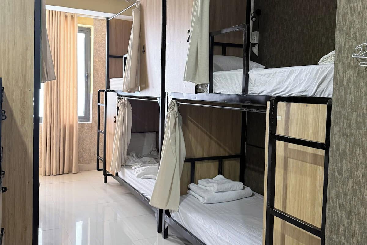 Une chambre de dortoir avec des lits superposés, une armoire en bois et un rideau.