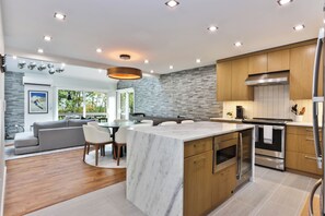 A modern kitchen with a marble island, wooden cabinets, stainless steel appliances, and recessed ceiling lighting. - Ski in/out @ Camelback: Sleeps up to 16 (Tannersville)