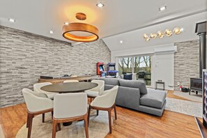 A modern living room with a dining area, grey sofa, wooden table, and a fireplace. - Ski in/out @ Camelback: Sleeps up to 16 (Tannersville)