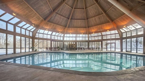 An indoor swimming pool with a wooden ceiling and large windows. - Ski in/out @ Camelback: Sleeps up to 16 (Tannersville)