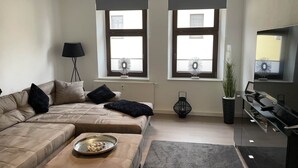 A modern living room with a sofa, ottoman, and a TV stand.