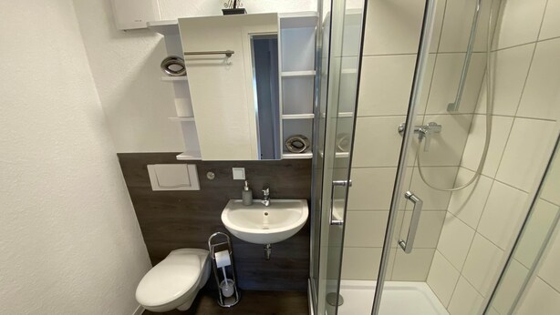 Un bany modern amb vàter, rentapel i plat de dutxa amb envàs de vidre.