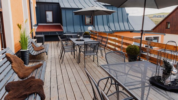 Une terrasse sur le toit, avec des sièges, une table et un grand parasol.