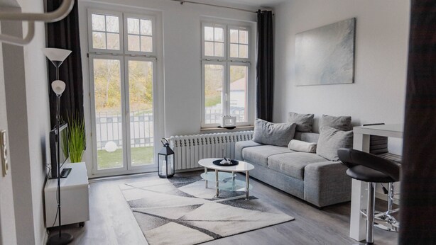 Een moderne woonkamer met een bank, een bijzettafeltje en een barstoel.