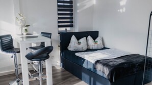 Een moderne kamer met een bed, een bureau en twee barkrukken.