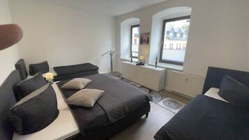 Une chambre à coucher avec un lit, des tables de chevet, une lampe, une fenêtre et un radiateur.